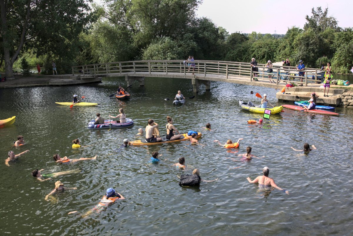 Members of the public swimming and canooing in a river