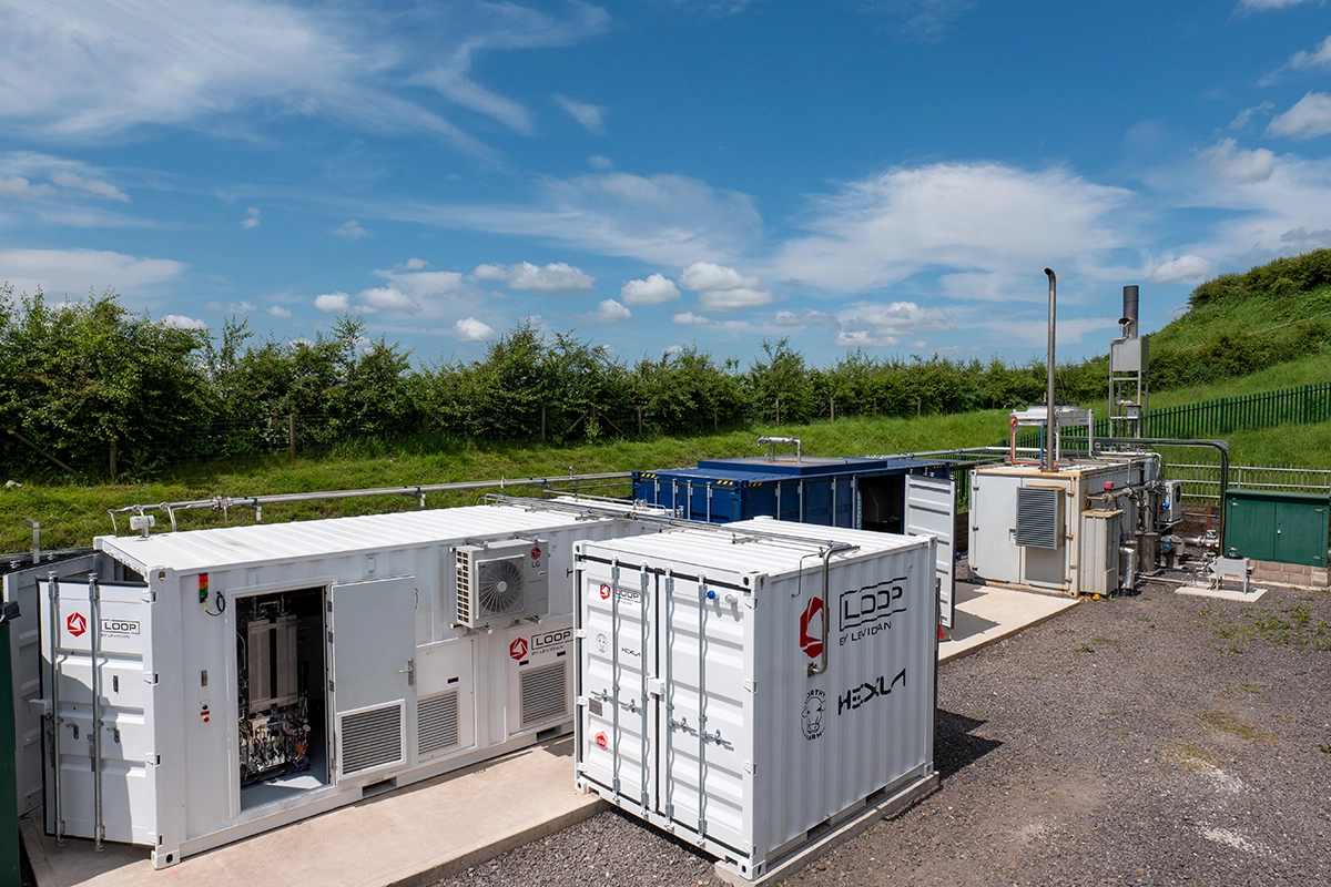 Enclosures bearing the LOOP and Hexla insignia, in an outdoor rural location, resembling a hillside