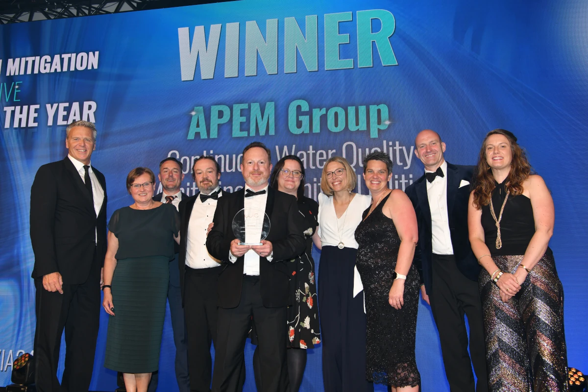 A group of 10 or so people in evening wear on a stage in front of the words